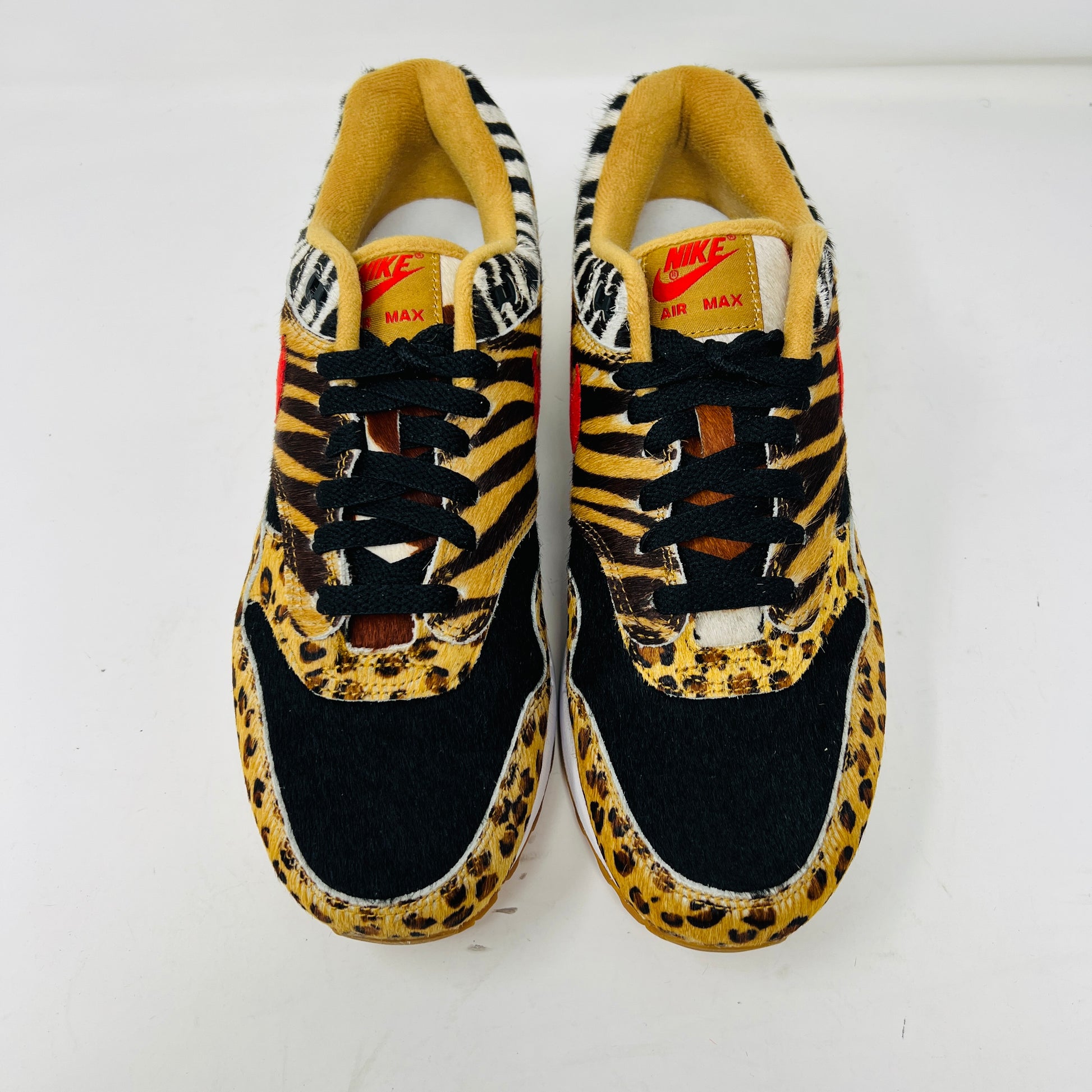 The Nike Air Max 1 Atmos Animal Pack 2.0 sneakers feature a striking leopard and zebra print with black laces, accented by red branding on the tongue.