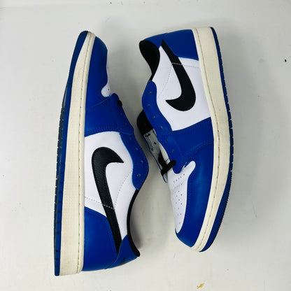 A Jordan 1 Retro Low OG Game Royal shoe in blue, white, and black is showcased on a matching blue Nike box. It features a black swoosh logo and the box label indicates size 12.