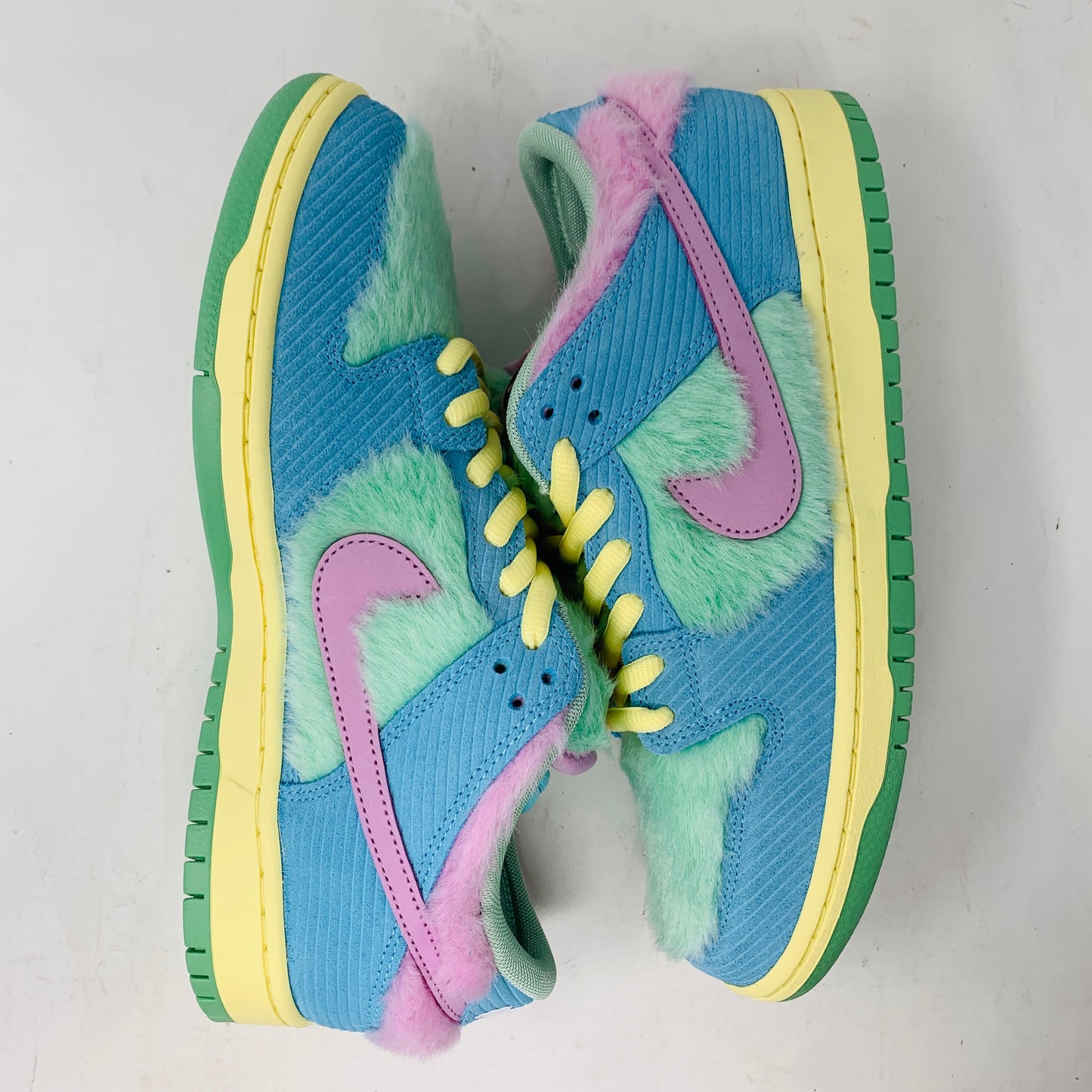 Brand new Nike SB Dunk Low Verdy Visty sneakers with blue, green, and pink fuzzy textures showcase pink swooshes, yellow laces, and green soles against a light gray background.