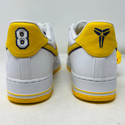 Nike Air Force 1 Low Retro QS Kobe Bryant Lakers Home features white sneakers with yellow heel accents, one shoe embroidered with a blue number 8, and the other showing a blue logo. The soles are textured in yellow. Brand: Nike.