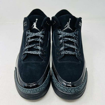 The Jordan 3 Retro Black Cat (2025) sneaker, featuring a glossy finish and elephant print accents, sits on a black box with the red Jumpman logo. This brand new, 100% authentic release from Jordan ensures style and exclusivity.