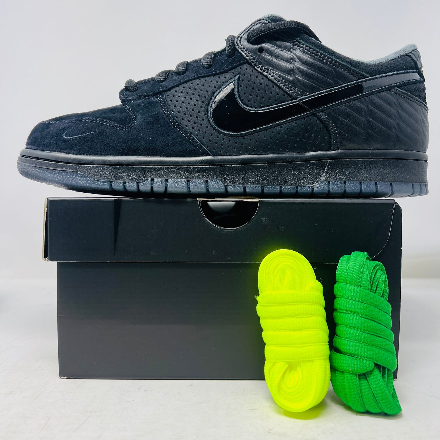 The Nike Dunk Low Ducks of a Feather Black University of Oregon PE sneaker proudly sits on its black shoebox, featuring a glossy swoosh logo. Included are two vibrant laces—bright yellow and green—and three extra laces to mix up your 100% authentic style. Brand new from Nike!.