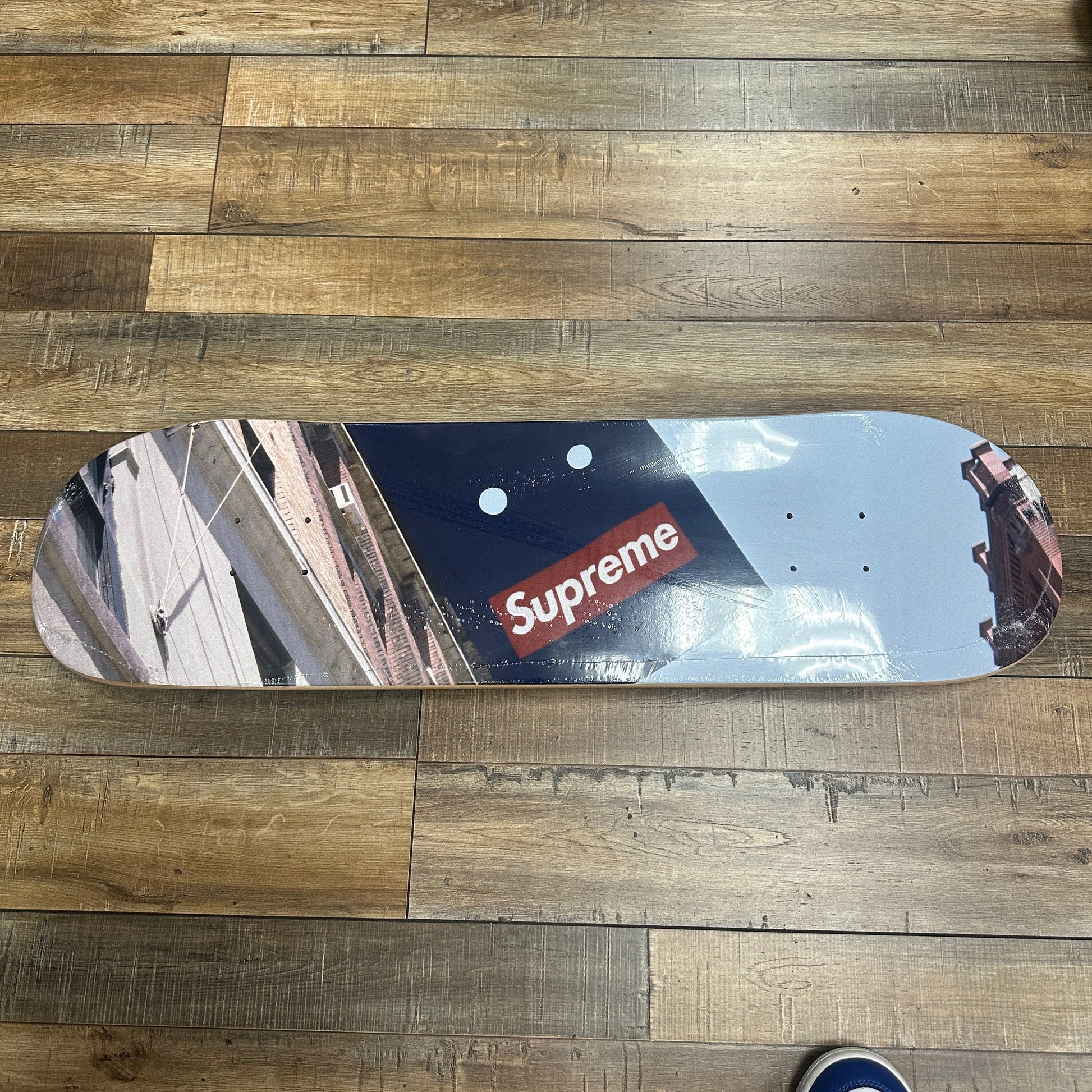 Supreme Banner Skateboard Deck with multi-colored design on wooden floor.