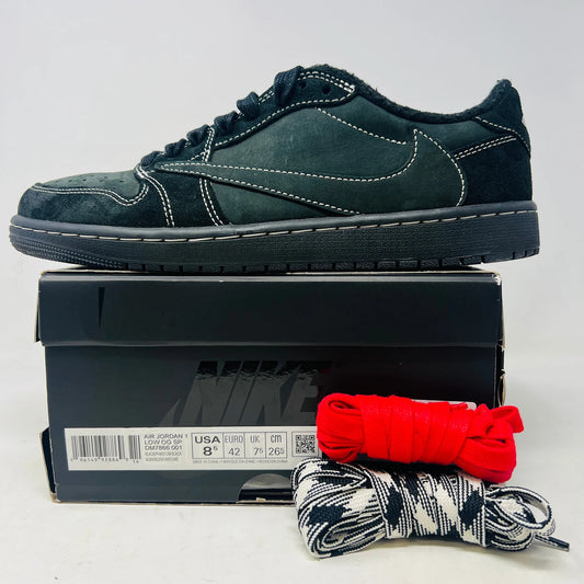 The Jordan 1 Retro Low OG SP Travis Scott Black Phantom sneaker is displayed on its box, highlighting a 100% authentic design. Extra laces include one red and another with a black-and-white pattern. With clean uppers and striking stitching, this elegant shoe from Jordan makes a statement.