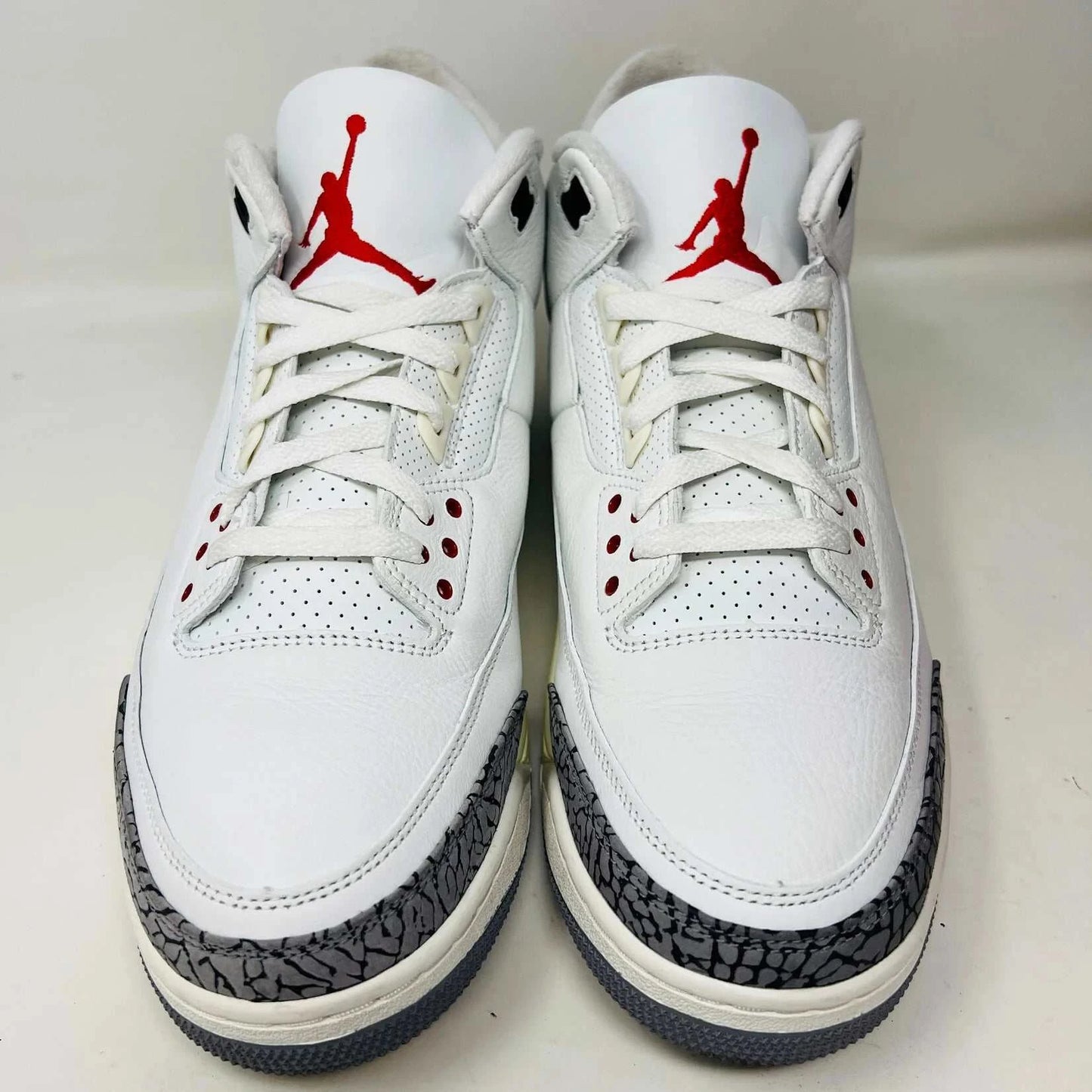 An authentic Jordan 3 Retro White Cement Reimagined sneaker with gray elephant print accents sits on its black Nike Air shoebox. It has red details and black branding, with the Nike Air logo on the heel and tongue. Released in 2023, box shows size 13.