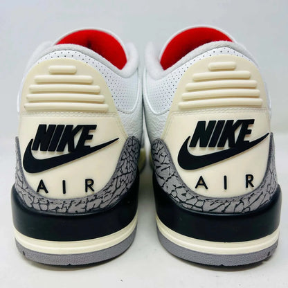 An authentic Jordan 3 Retro White Cement Reimagined sneaker with gray elephant print accents sits on its black Nike Air shoebox. It has red details and black branding, with the Nike Air logo on the heel and tongue. Released in 2023, box shows size 13.