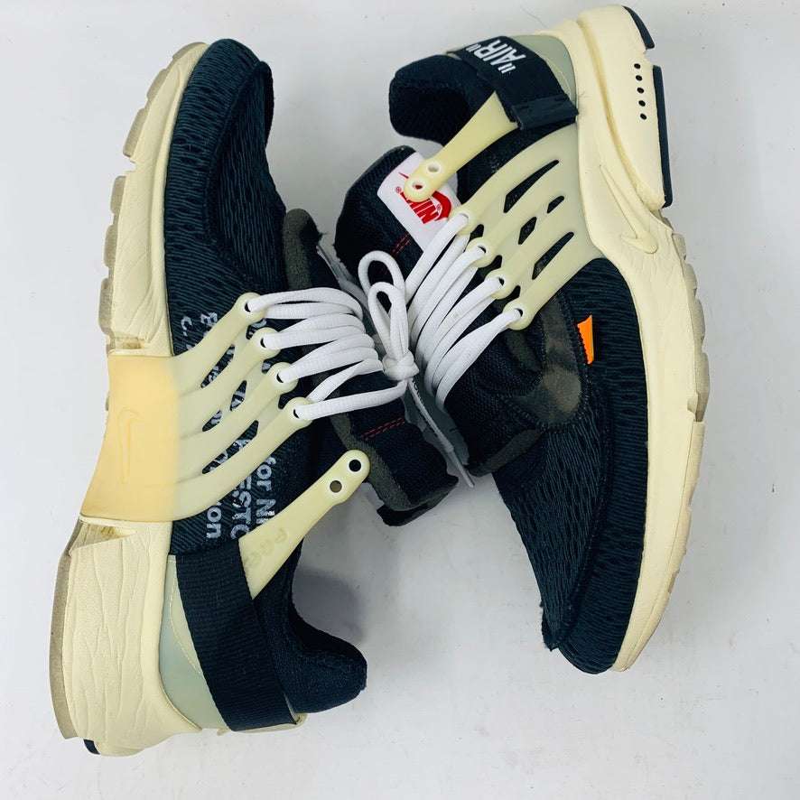 A pair of authentic Nike Air Presto Off-White sneakers featuring black uppers, cream soles, and white laces. They showcase a unique design with a red tag and orange side accents against a plain white backdrop.