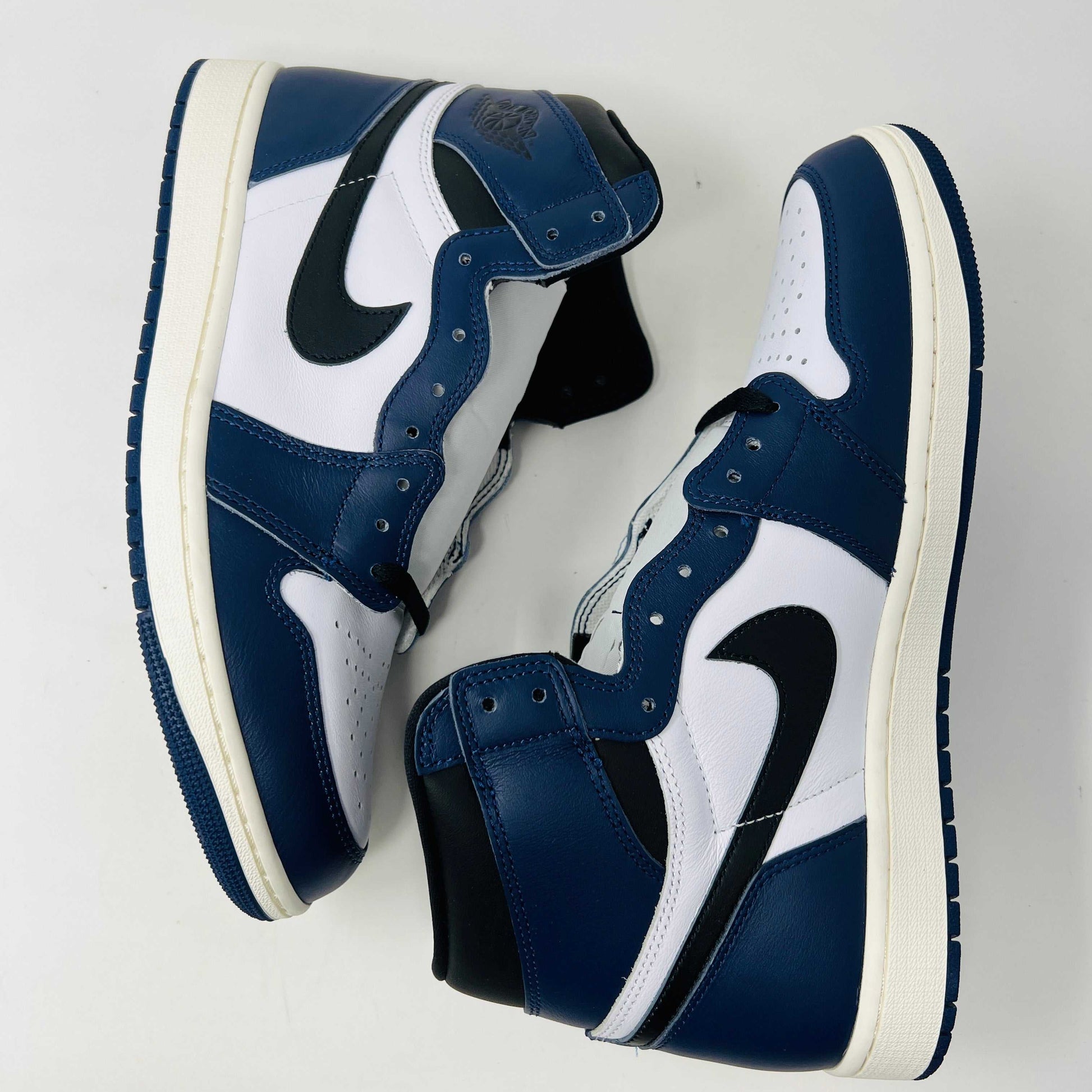 A brand new Jordan 1 Retro High OG Midnight Navy high-top sneaker, featuring navy blue, white, and black colors with the iconic swoosh and Air Jordan logo, displayed on a matching shoe box.