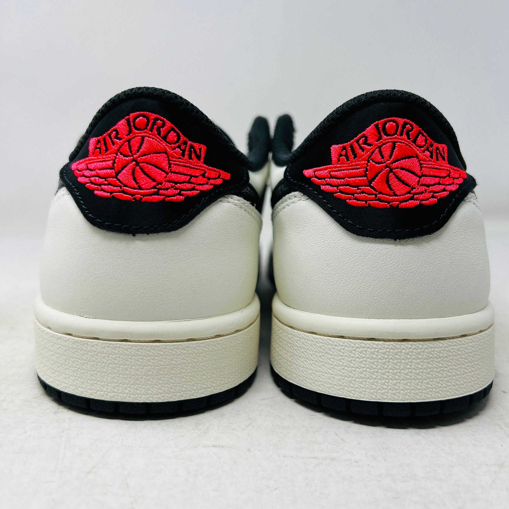 Authentic, brand new Jordan 1 Retro Low OG PSG Paris Saint-Germain sneakers by Jordan are displayed on a matching shoebox. The shoes feature a textured black swoosh and striking red toebox against a plain white background.