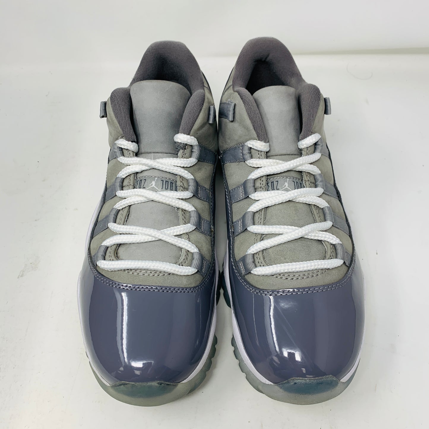 The Jordan 11 Retro Low Cool Grey by Jordan, shown on a white background, features gray and white athletic sneakers with clean uppers, glossy toe caps, and white laces. Ideal for those seeking style in size 9.5.