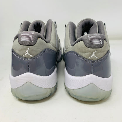 The Jordan 11 Retro Low Cool Grey athletic shoes feature a glossy gray and white design with the Jumpman logo on the heel, soft gray fabric uppers, and translucent soles. Available in size 9.5, they blend style and comfort effortlessly.