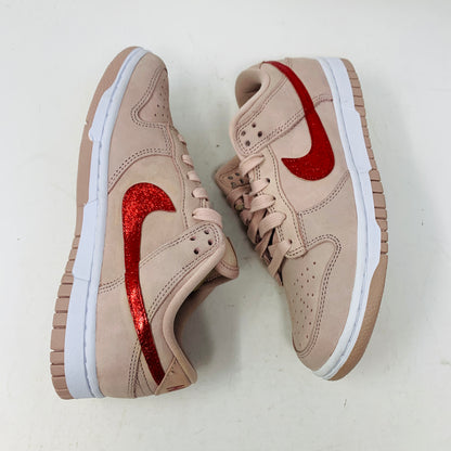 The Nike Dunk Low PRM Pink Oxford (W) Valentines Day CUSTOM sneakers feature a beige body, red glittery swoosh logos, white midsoles, and beige laces. Displayed against a white background, these sneakers highlight a stylish and sporty look.