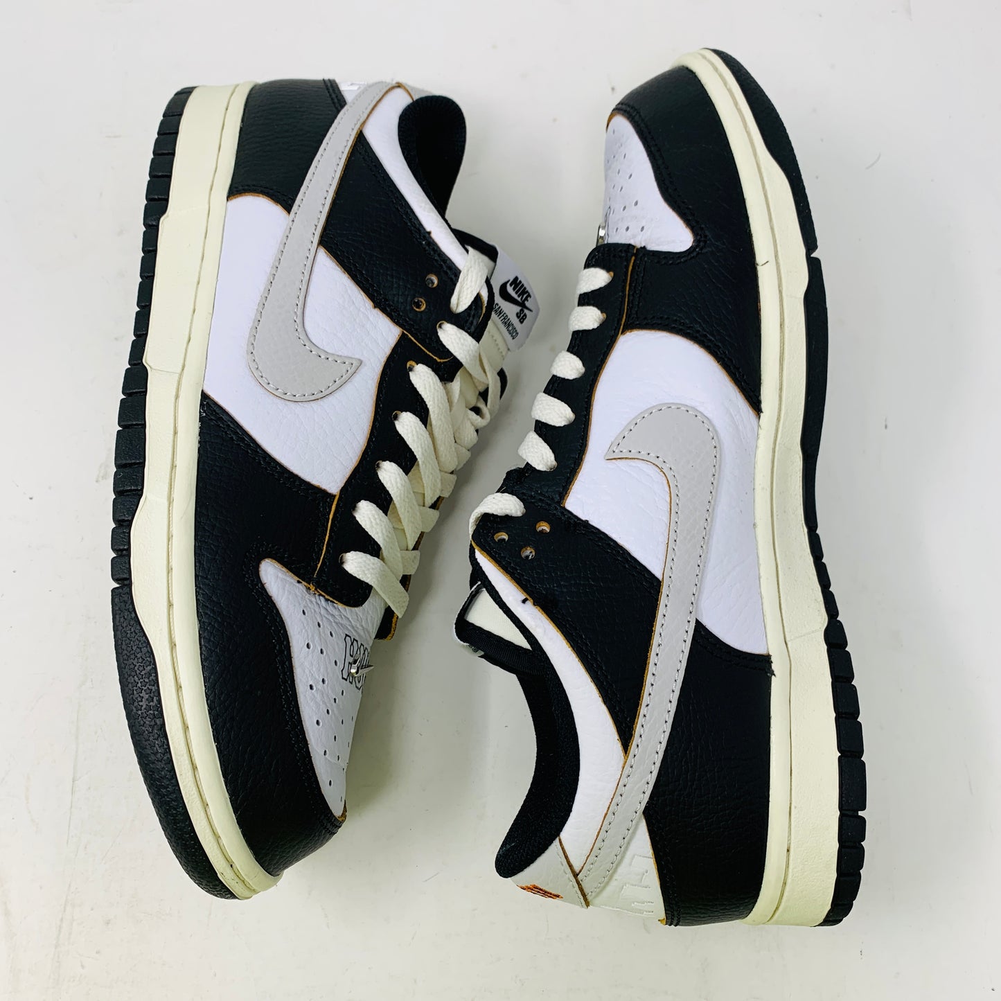 The Nike SB Dunk Low HUF San Francisco sneakers, released in 2022, showcase a classic black and white design with a sleek swoosh logo, black laces, and a resilient black sole accented with white trim on a pristine white background, embodying timeless style.