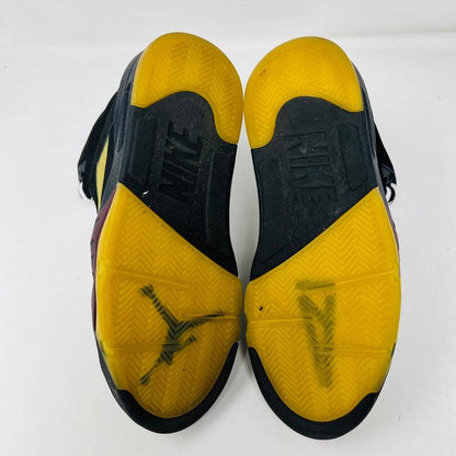 The Jordan 5 Retro A Ma Maniére Dusk by Jordan showcases black and yellow soles with the Nike logo. The yellow parts have black marks, while the tread combines herringbone and groove designs, ideal for dusk-time adventures.