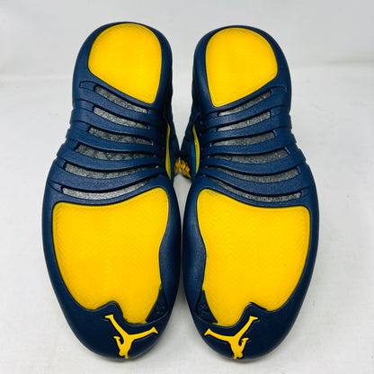 The Jordan 12 Retro Michigan is a blue high-top sneaker with yellow accents from Jordans 2018 Shoes collection. It features a textured surface, stitching details, and a visible Jumpman label. The dark blue sole highlights its vibrant design against a white background.