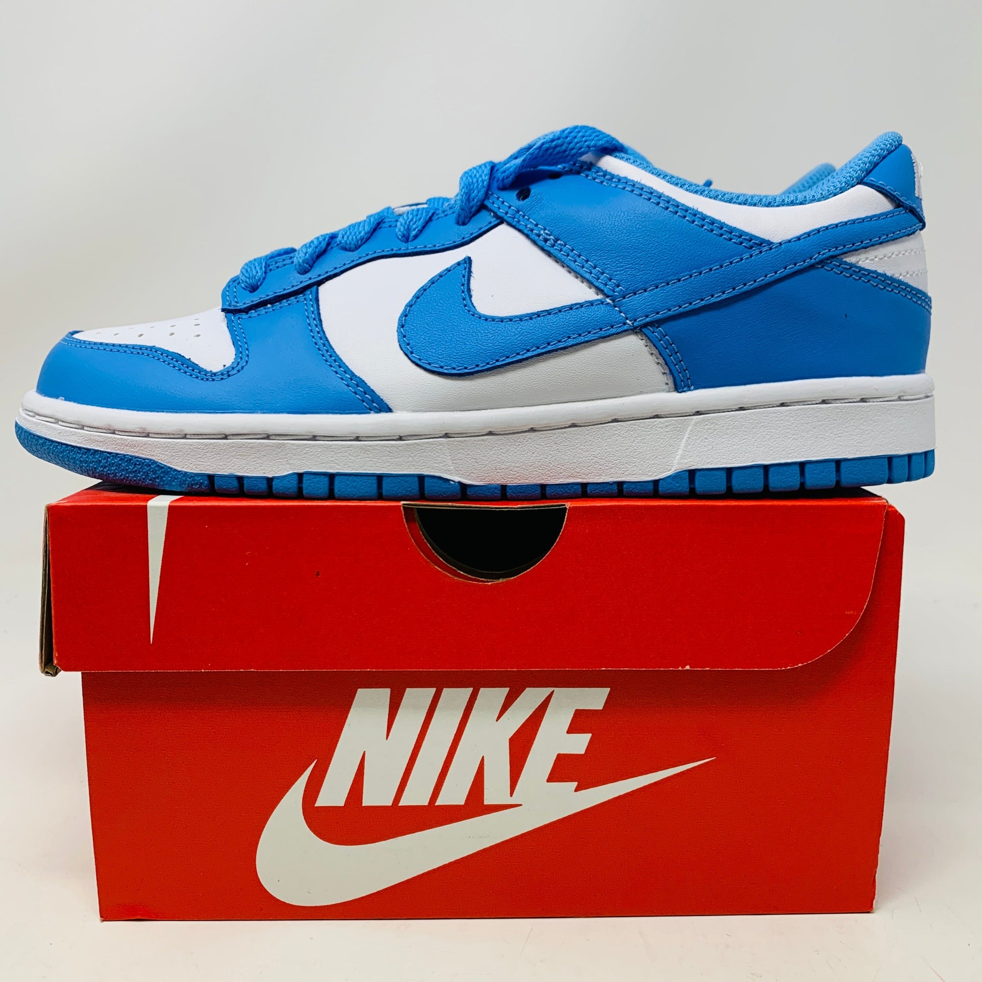 Nike Dunk Low UNC GS shoes in blue and white on a red Nike box.