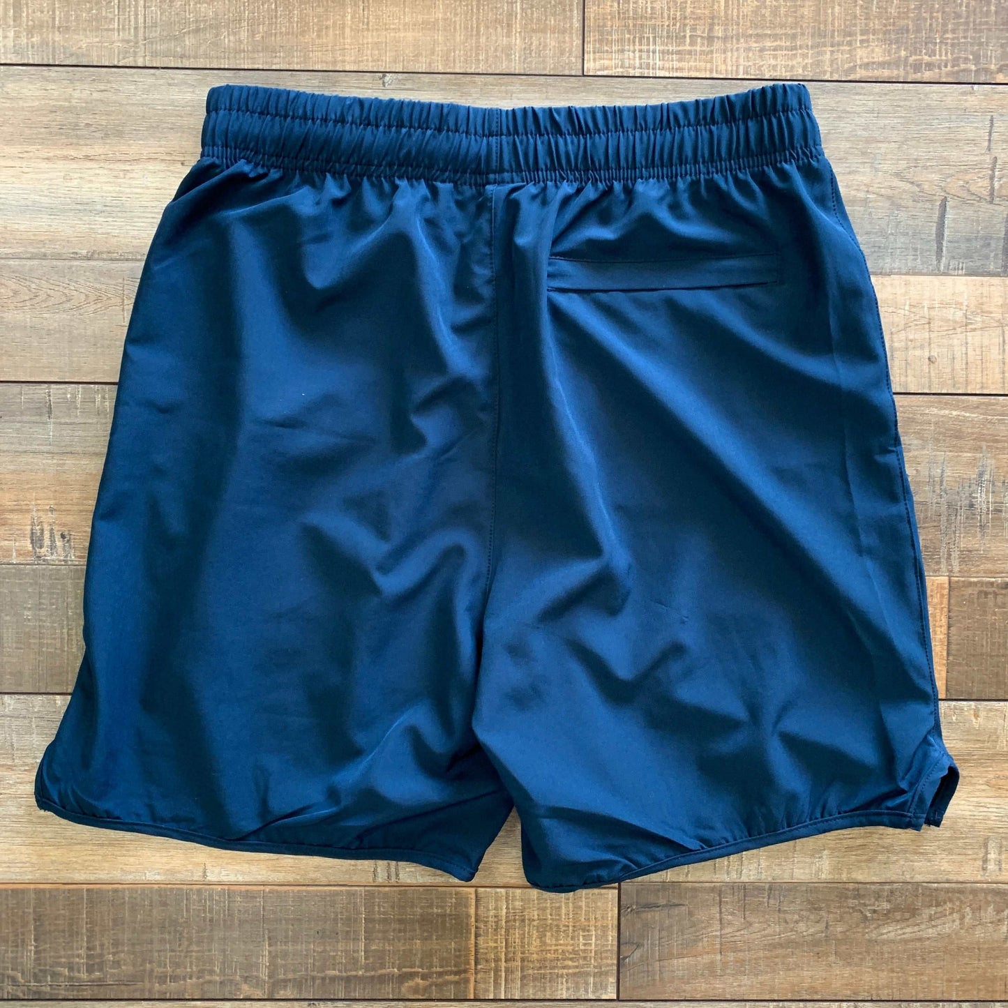 Blue athletic shorts with elastic waistband, Holy Ground logo, side pockets, lightweight fabric.