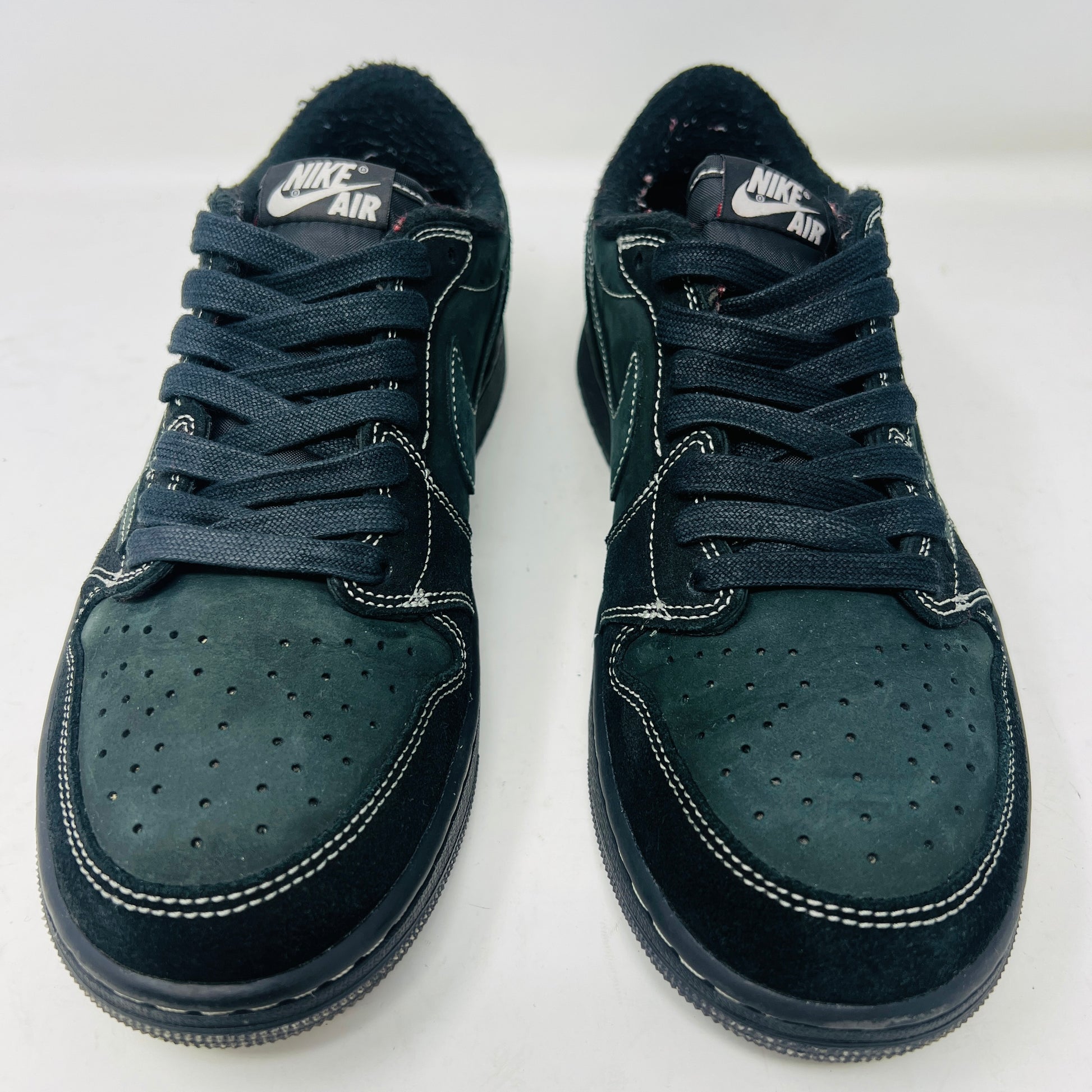 The Jordan 1 Retro Low OG SP Travis Scott Black Phantom is a stylish sneaker featuring a dark green suede upper with black leather accents, packed in a black shoebox. It comes with red and black-and-white patterned spare laces, showcasing its original swoosh design.