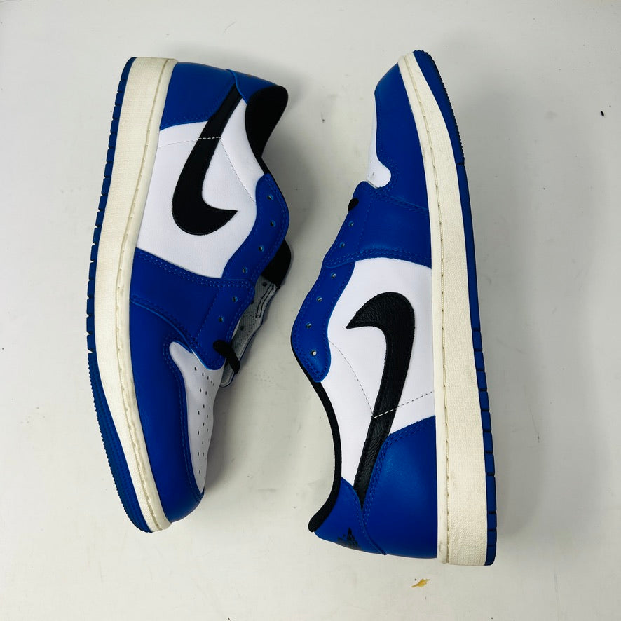 A Jordan 1 Retro Low OG Game Royal shoe in blue, white, and black is showcased on a matching blue Nike box. It features a black swoosh logo and the box label indicates size 12.