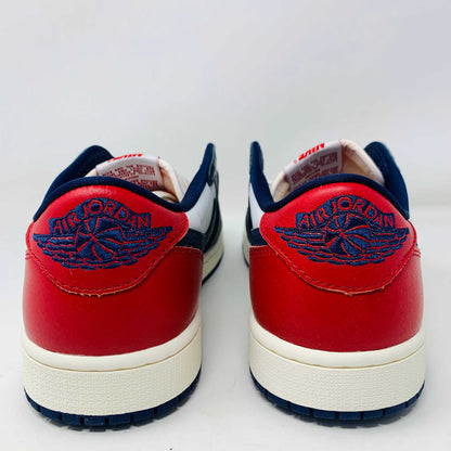 The Jordan 1 Retro Low OG Howard University sneaker, in navy, white, and red with a white midsole and Nike swoosh, rests on the shoe box. A small brown box with extra laces is placed in front.