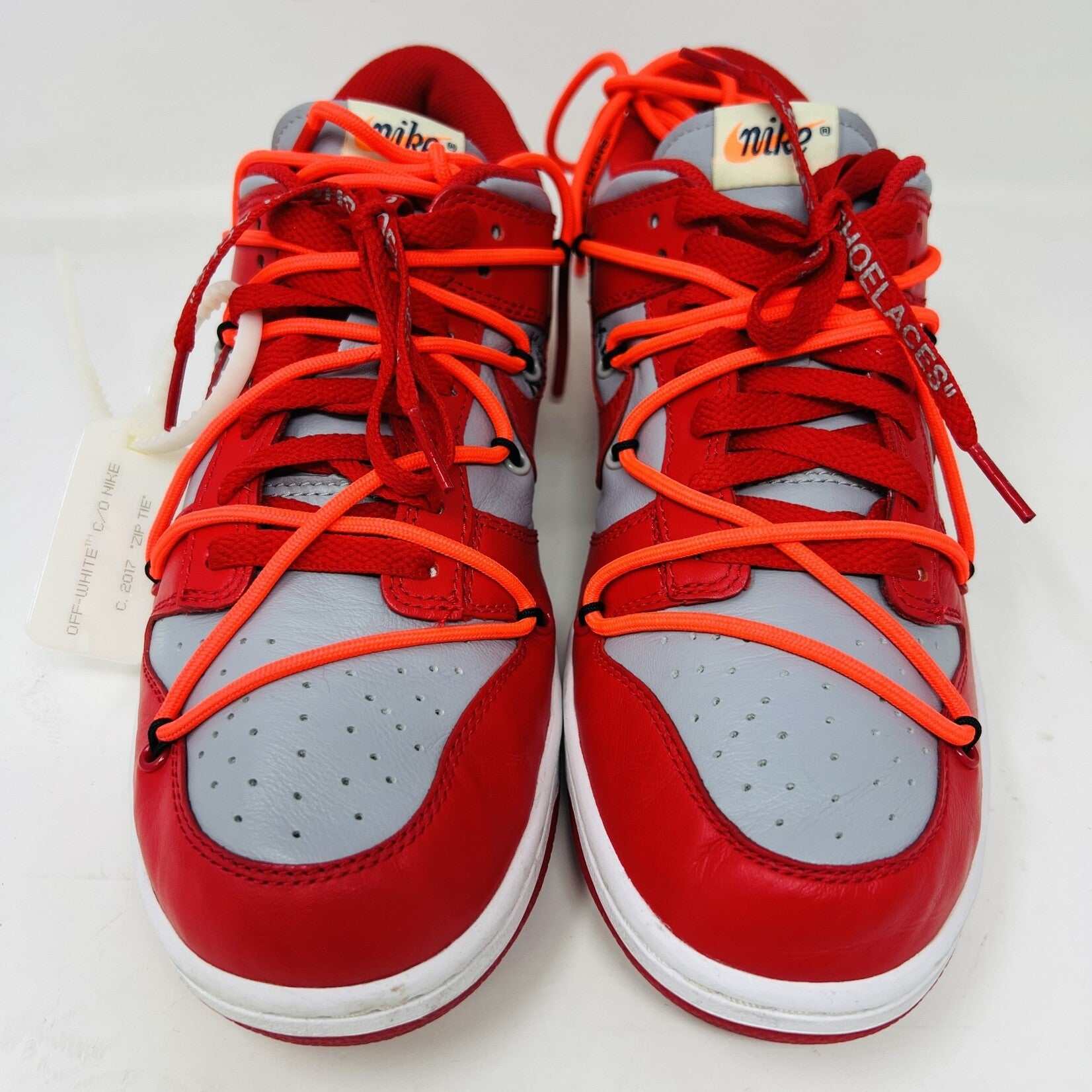 The Nike Dunk Low Off-White University Red sneakers with orange laces, from Holy Ground, are clean and authentic, showcased atop a white shoebox displaying size and product details.