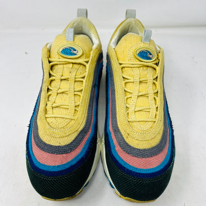 The Nike Air Max 1/97 Sean Wotherspoon sneakers feature a layered design in yellow, blue, pink, and gray with a wave logo on the tongue. These authentic shoes have a textured upper stitched intricately for an eye-catching finish against a white background.