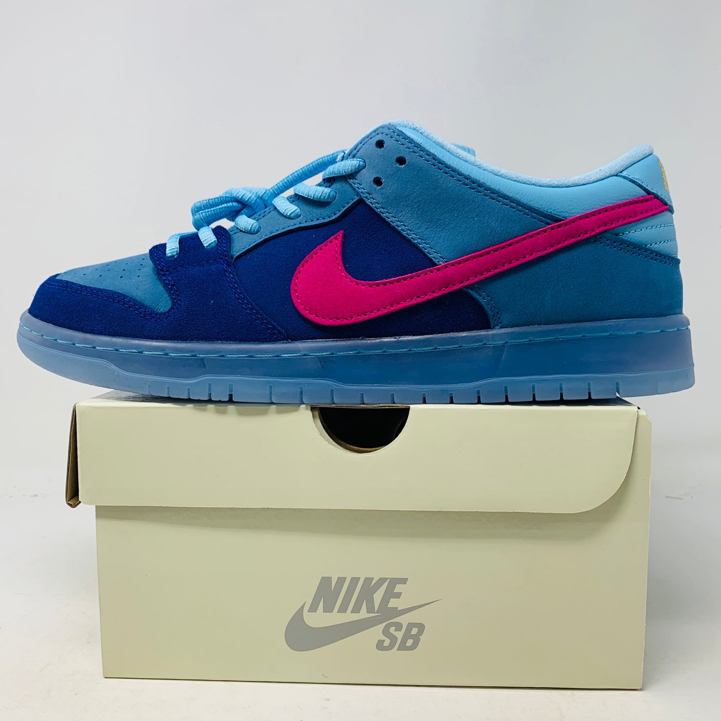 Blue Nike SB Dunk Low Run the Jewels sneakers on a box, featuring pink swoosh and black sole.