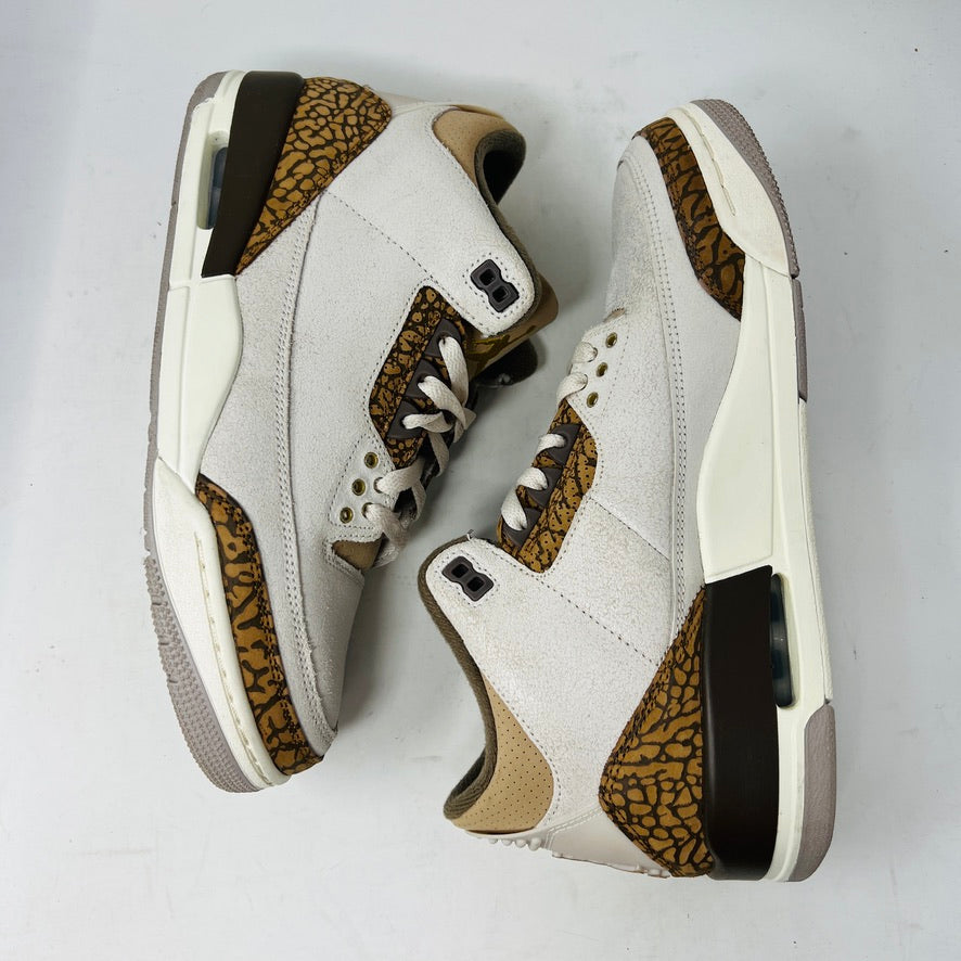 The Jordan 3 Retro Palomino, from the 2023 collection, features clean beige and brown uppers, textured brown accents, white laces, and a white midsole with a visible air unit. Its paired with a unique green and gray patterned replacement box.