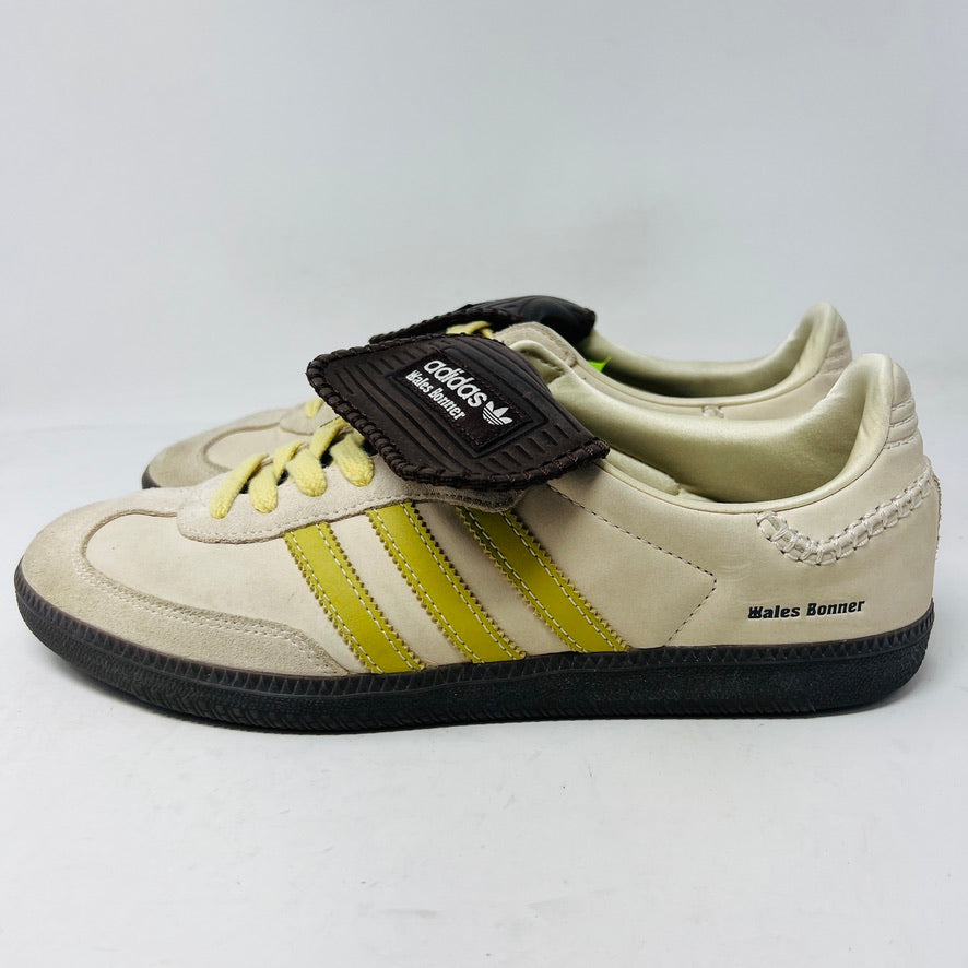 The 2023 adidas Samba Wales Bonner Ecrtin Brown sneakers feature beige uppers with three yellow stripes, a brown logo flap, and black soles. Despite general wear, the side and tongue branding stays distinct. Theyre displayed side by side on a white background.