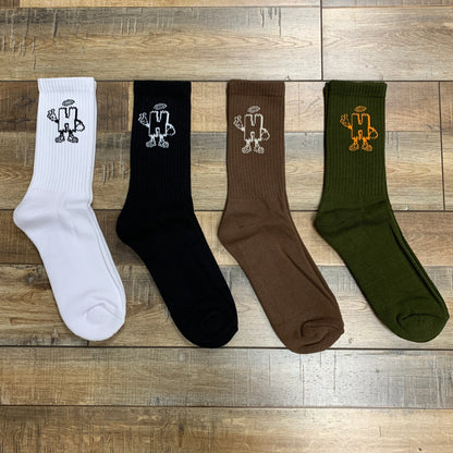 Holy Ground Socks in white, black, brown, and green on wooden floor.