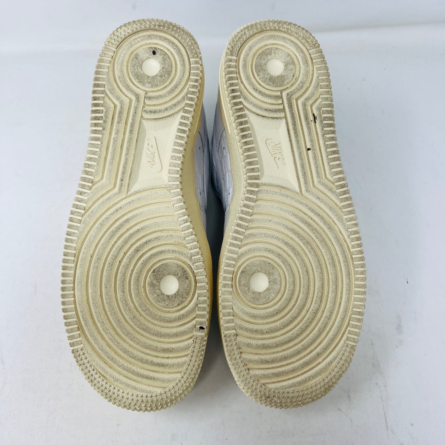 The image shows the soles of 100% authentic Nike Air Force 1 Low Kith Paris sneakers with circular tread patterns and light general wear on the white surface.