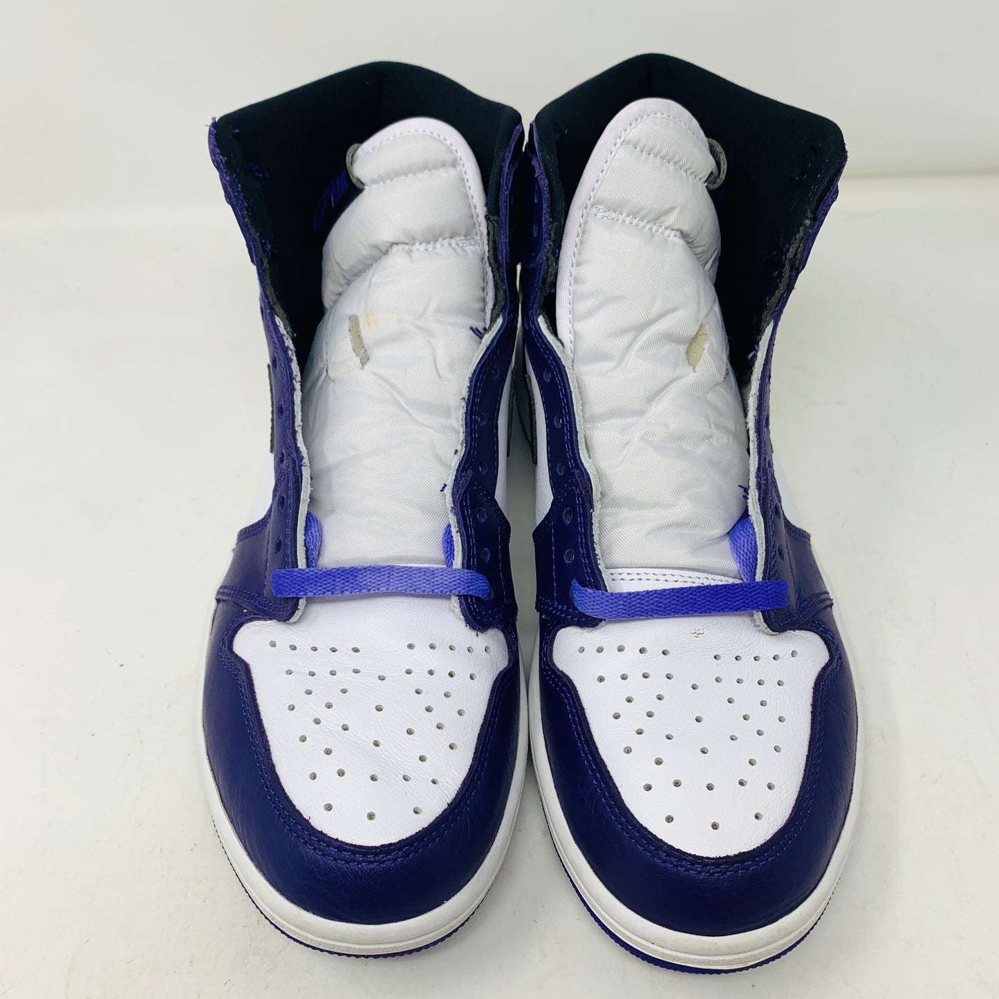 The Jordan 1 Retro High Court Purple White by Jordan, a genuine high-top sneaker in size 9.5, showcases white perforated toe boxes, dark blue leather overlays, and matching blue laces. They are elegantly displayed side by side on a plain white background.