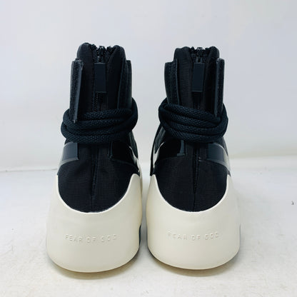 The Nike Air Fear Of God 1 SA Black, with its futuristic black high-top design, features a white sole, glossy black swoosh logo, distinctive lace loops, and an ankle velcro strap. This authentic sneaker sits atop an orange shoe box.