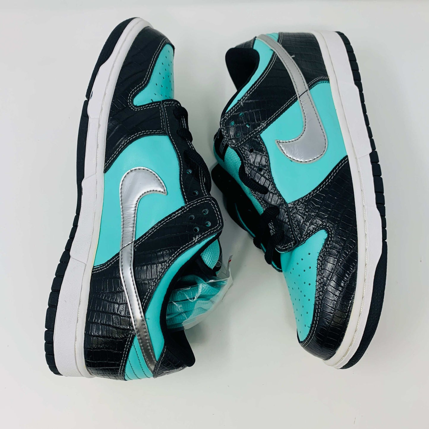 Nike SB Dunk Low Diamond Supply Co sneakers in black and turquoise with silver Swoosh and crocodile texture accents.