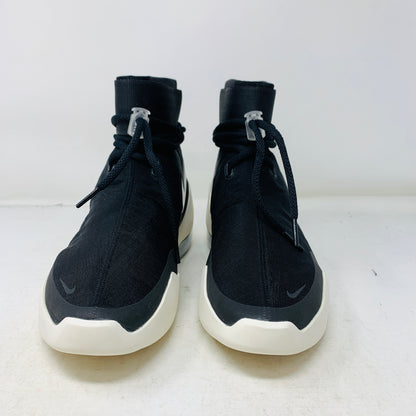 The Nike Air Fear Of God 1 SA Black, with its futuristic black high-top design, features a white sole, glossy black swoosh logo, distinctive lace loops, and an ankle velcro strap. This authentic sneaker sits atop an orange shoe box.