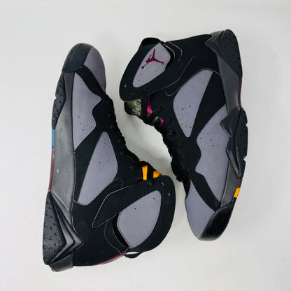 The Jordan 7 Retro Bordeaux (2015) sneakers, in black and gray with maroon accents and the Jumpman logo, feature angular midsoles, dark laces, and sleek uppers. They evoke a 2015 vibe and are photographed side by side on a white background.