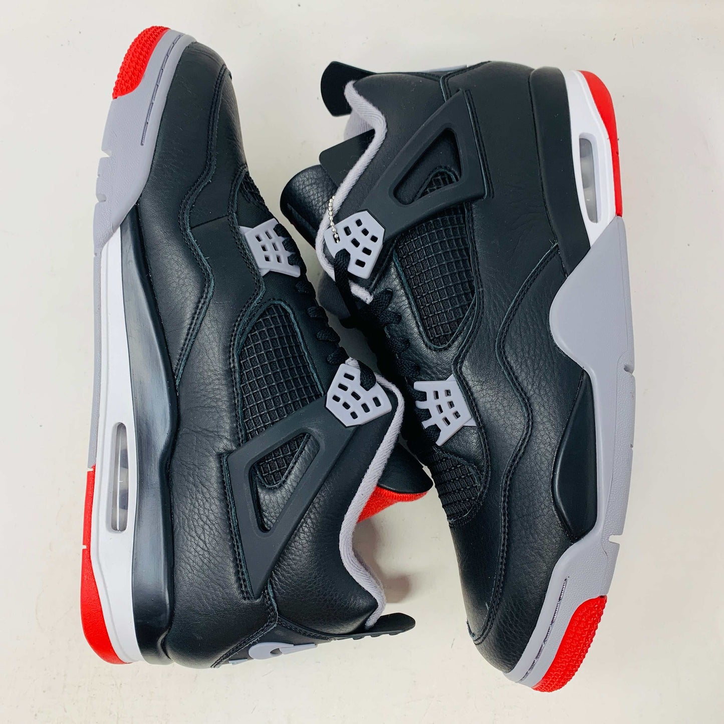 Jordan 4 Retro Bred Reimagined sneaker with black and red colorway, leather and mesh upper, Jumpman logo on tongue and heel, Nike Air branding on heel tab.