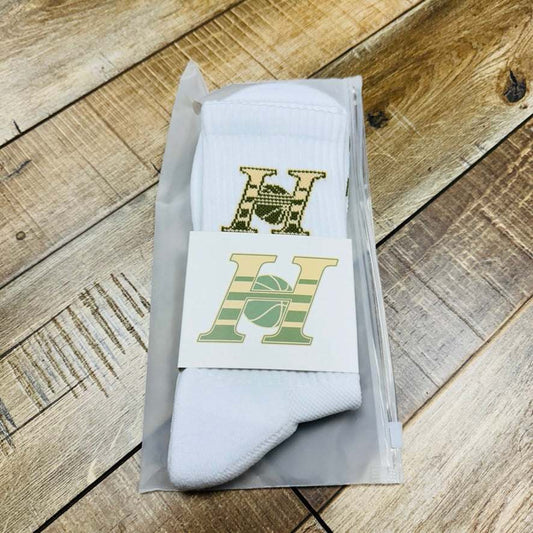 HG Elite Socks in packaging on wooden floor, featuring high-quality athletic design and logo.