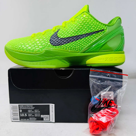 The Nike Kobe 6 Protro Grinch (2020) features bright green uppers with a textured design and a black Nike swoosh, resting on a black shoe box with size details and branding. It includes extra red and black laces in a clear plastic bag for an authentic touch.