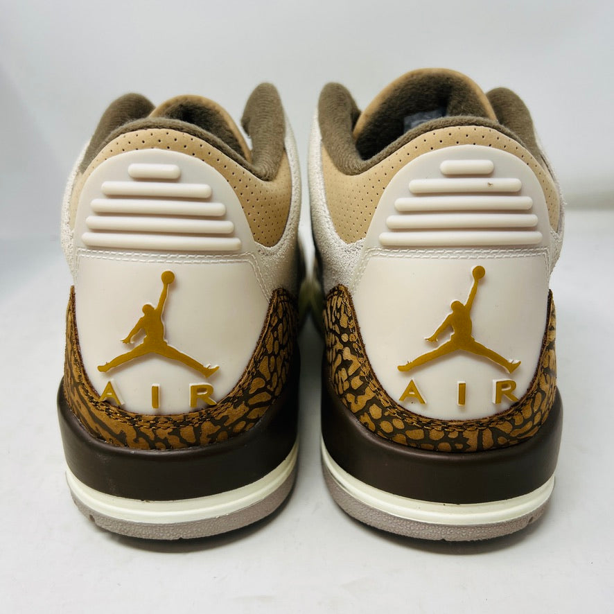 The Jordan 3 Retro Palomino, from the 2023 collection, features clean beige and brown uppers, textured brown accents, white laces, and a white midsole with a visible air unit. Its paired with a unique green and gray patterned replacement box.