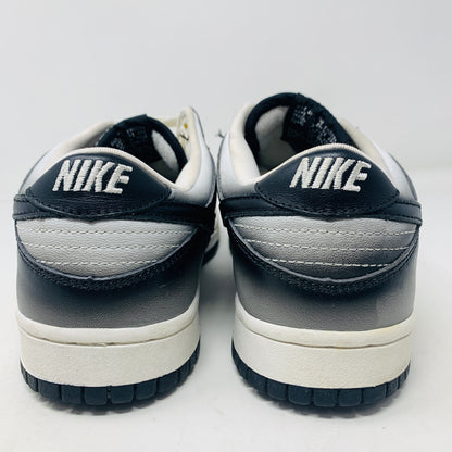 Rear view of a pair of Nike Dunk Low Haze 2003 sneakers, featuring the brand logo on the heel, set against a plain white background.