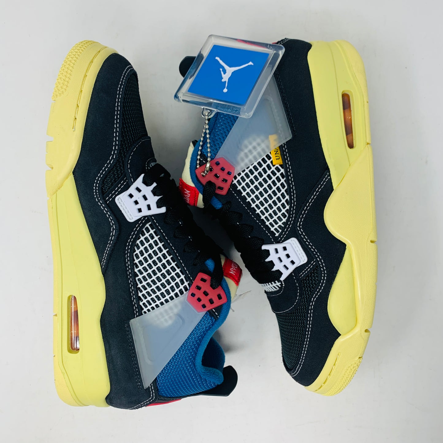 The Jordan 4 Union Noir sneaker in black, yellow, blue, and red is 100% authentic and brand new. It features a visible air unit in the heel, a translucent tab with the Jumpman logo, a matching shoebox, and extra laces for versatility.