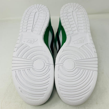 The image displays the soles of Nike SB Dunk Low Heineken athletic shoes, featuring white textured bottoms with circular patterns and grooves, while the midsole and sides are green and white.