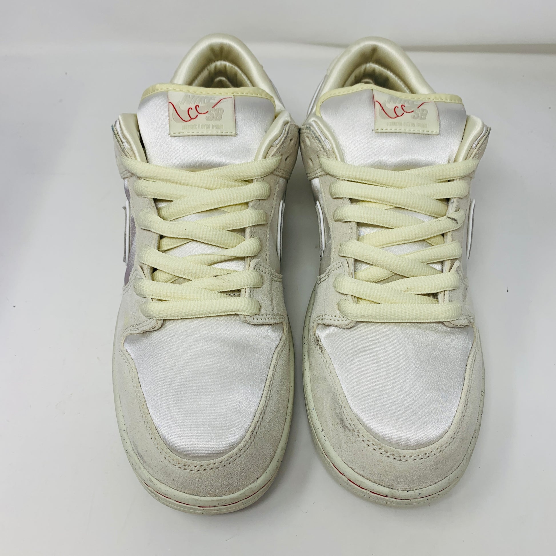 The Nike SB Dunk Low City of Love Light Bone sneakers, featuring a low-top design and subtle logo details on the tongue, are presented with cream-colored laces against a white background.