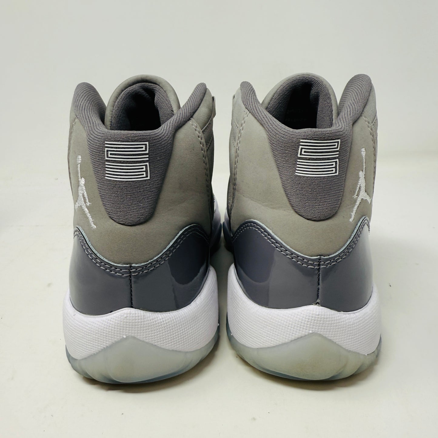 The Jordan 11 Retro Cool Grey (2021) (GS) sneakers by Jordan feature glossy patent leather overlays, a Jumpman logo on the heel, clean white uppers, and laces. They are displayed on a pristine Nike shoebox with size and model details labeled.