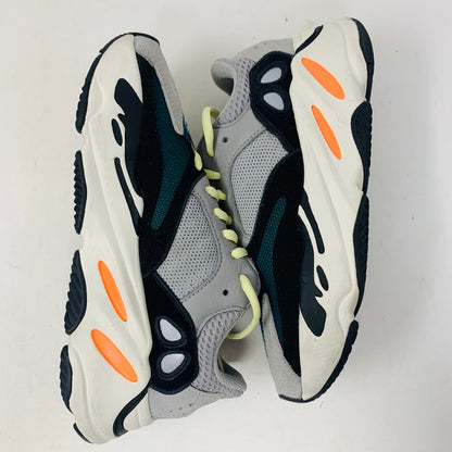 The Yeezy adidas Yeezy Boost 700 Wave Runner features a gray, black, and white design with bright orange accents and neon green laces on a white background, complete with a chunky sole.