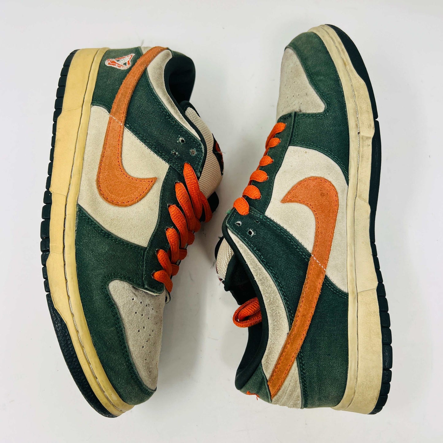 The Nike SB Dunk Low Eire by Holy Ground features a green and beige colorway with an orange swoosh and logo detail on the heel. It comes with a black box, extra Nike laces, ensuring authenticity and versatility.