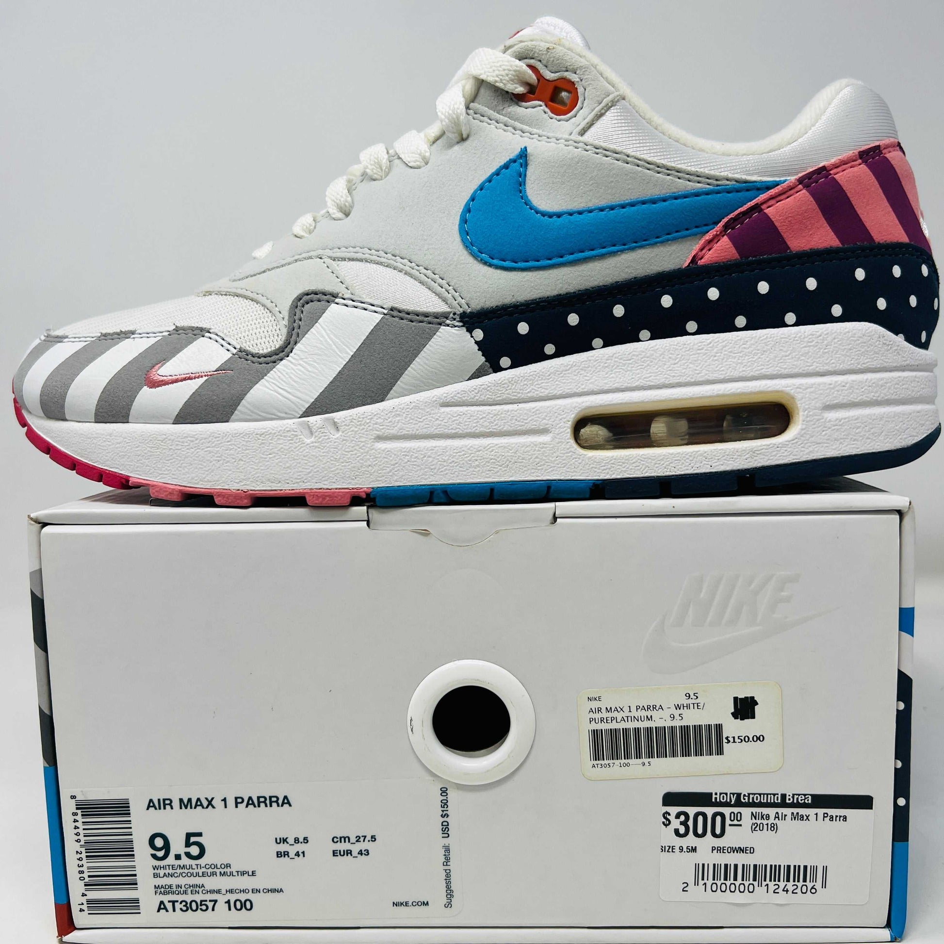 A Nike Air Max 1 Parra (2018) sneaker with clean uppers displaying stripes and polka dots sits on a box. The size 9.5 shoe features a blue swoosh and red, white, black accents, with visible original and discounted price tags ensuring authenticity.