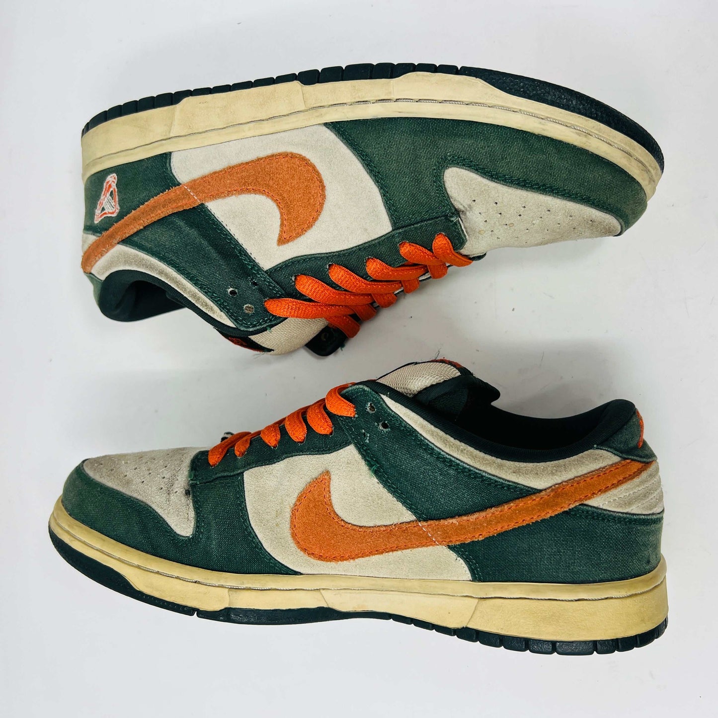 The Nike SB Dunk Low Eire by Holy Ground features a green and beige colorway with an orange swoosh and logo detail on the heel. It comes with a black box, extra Nike laces, ensuring authenticity and versatility.