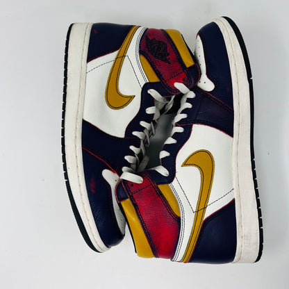 The Jordan 1 Retro High OG Defiant SB LA to Chicago features a colorful design with navy, red, white, yellow, and black accents. These high-top sneakers have a distinctive pattern, a logo on the side, and black soles with white trim.